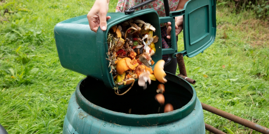 home composting a small trash can of food waste being deposited into a compost bin