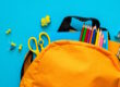 student backpack with school supplies with blue background