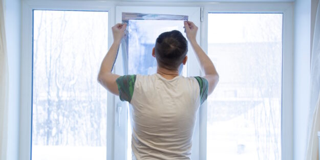 man applying window tint to the inside of three home doors and windows