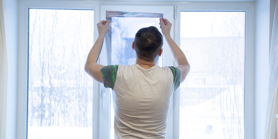 man applying window tint to the inside of three home doors and windows
