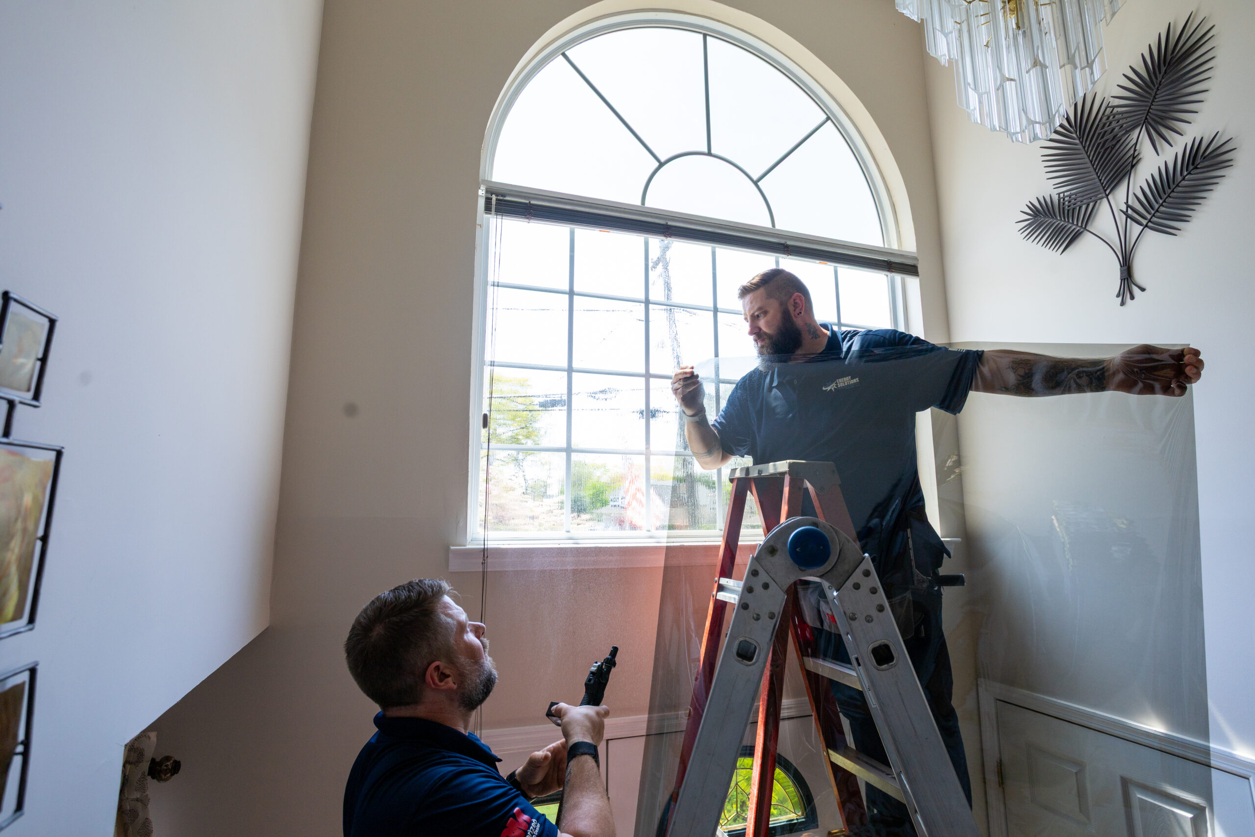 Energy Solutions Window Tinting applying their window film in a customer's home.