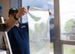 Energy Solutions Window Tinting applying window film to a large glass window to help reduce energy costs and improve energy efficiency.