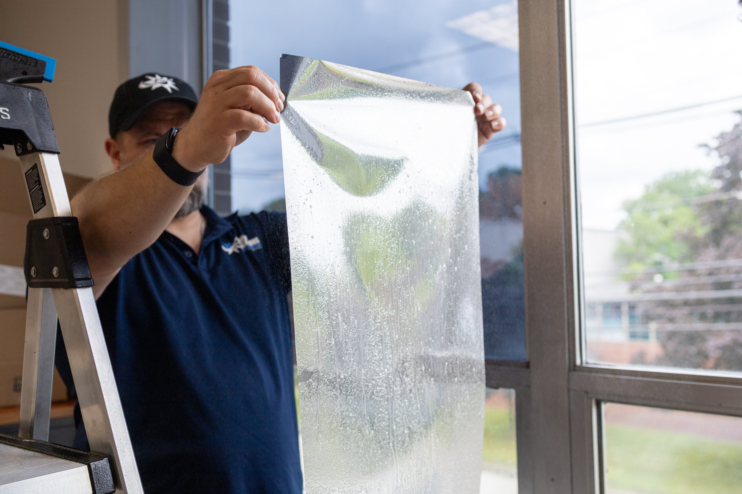Energy Solutions Window Tinting applying window film to a large glass window to help reduce energy costs and improve energy efficiency.