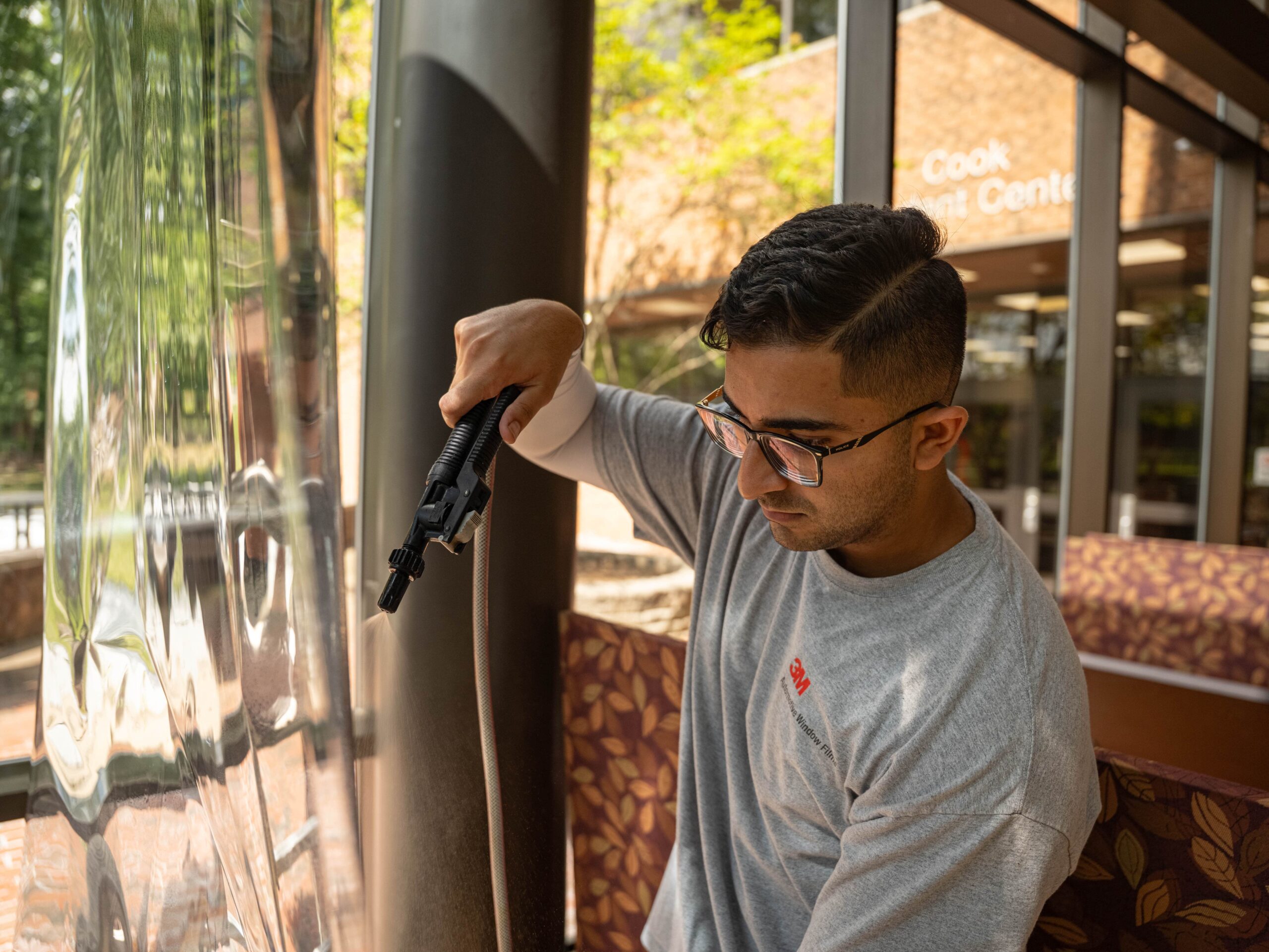 Energy Solutions Window Tinting employee applying commercial window film to a large glass window at Rutgers University.